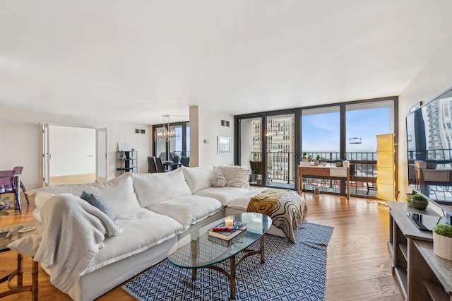 living area with a wall of windows, wood finished floors, visible vents, and an inviting chandelier