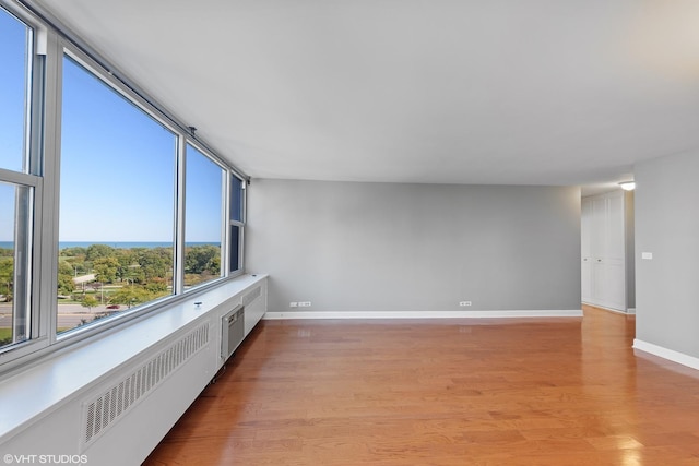 spare room with light wood finished floors, radiator heating unit, and baseboards