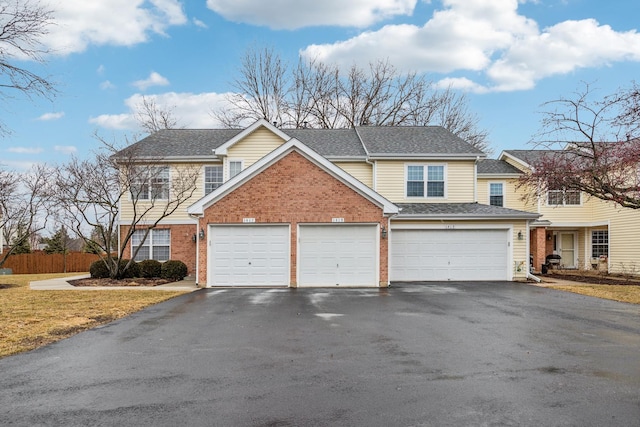 view of front of home with a garage, driveway, a shingled roof, and brick siding