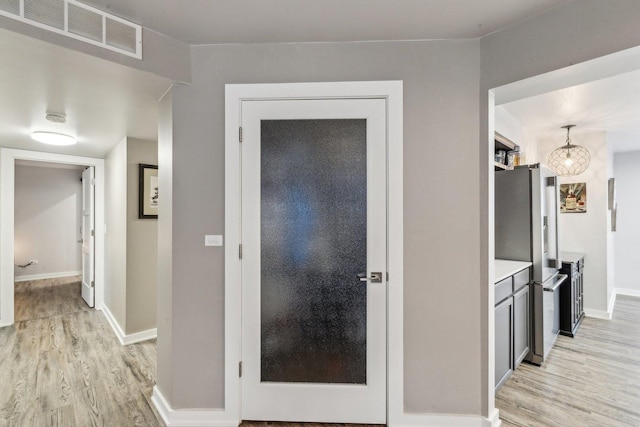 corridor featuring light wood-style floors, visible vents, and baseboards