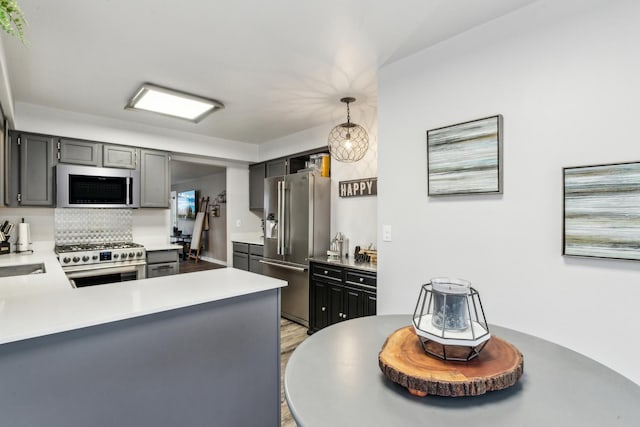 kitchen featuring premium appliances, backsplash, light countertops, light wood-type flooring, and a sink