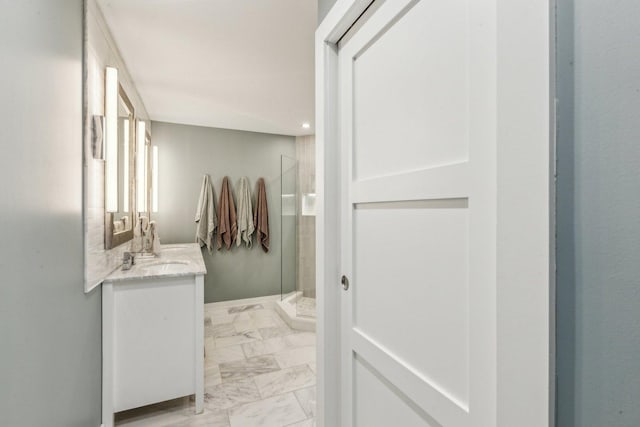 bathroom with marble finish floor, a shower stall, and vanity