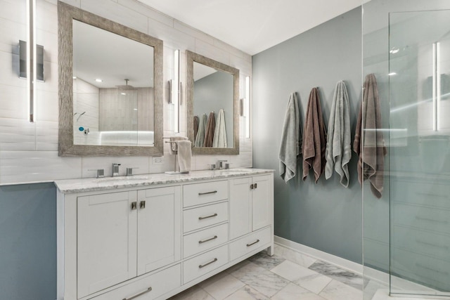 full bath featuring a sink, baseboards, marble finish floor, a shower stall, and double vanity