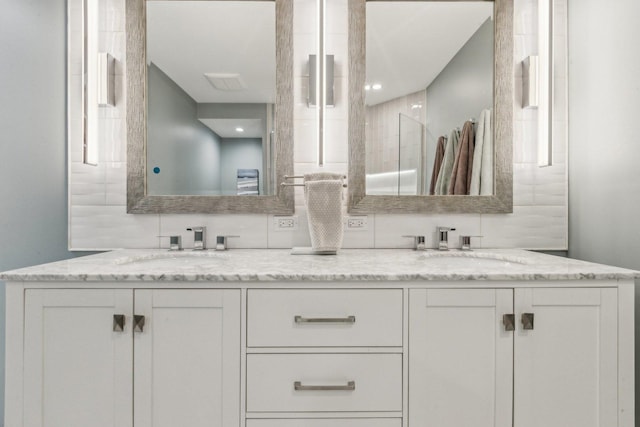 full bathroom featuring double vanity, a shower, and a sink