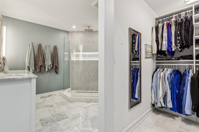 bathroom featuring a walk in closet, marble finish floor, and a shower stall