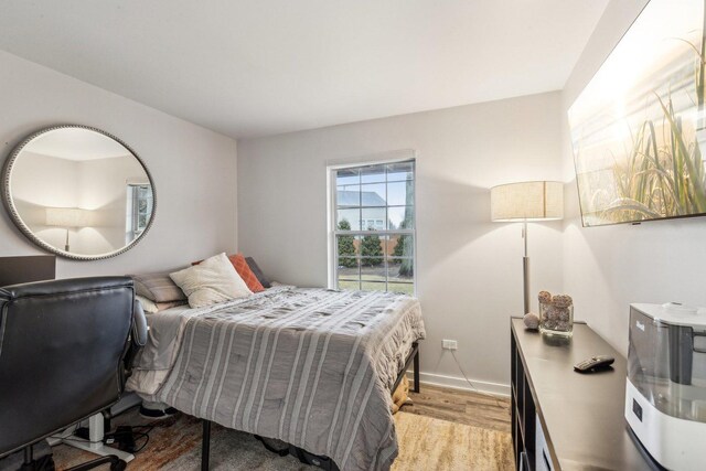 bedroom with light wood finished floors and baseboards