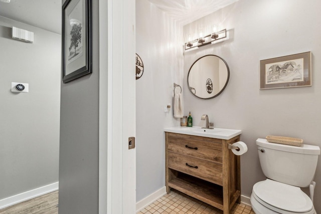 bathroom with toilet, baseboards, and vanity