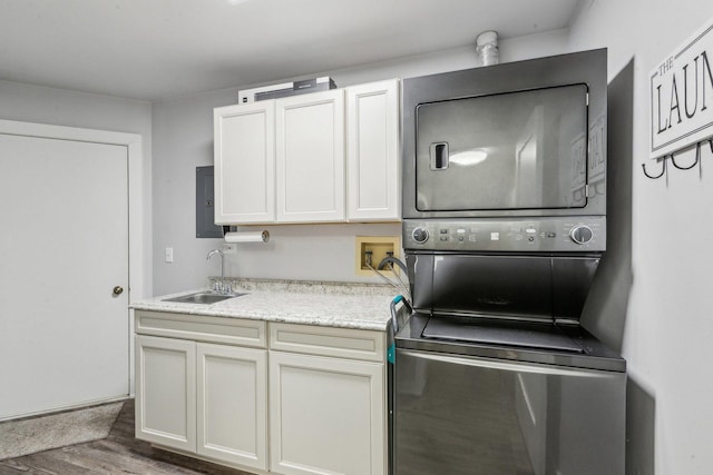 kitchen with stacked washer and dryer, a sink, and wood finished floors