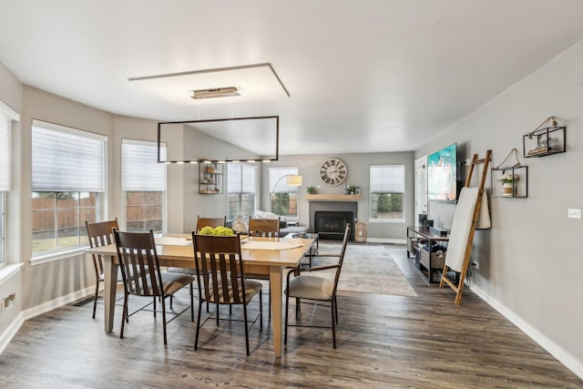 dining area with a fireplace, baseboards, and dark wood finished floors