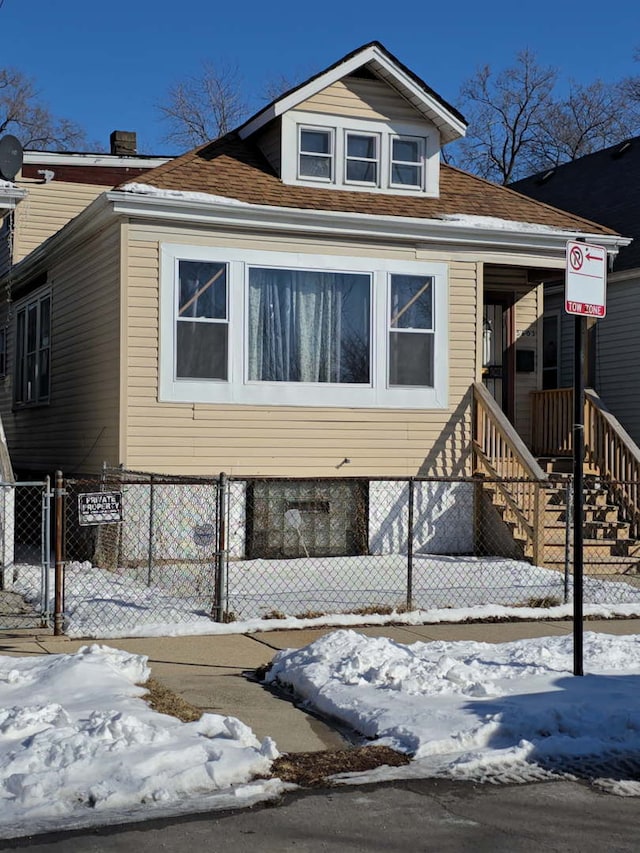 view of front of home with roof with shingles, fence, and a gate