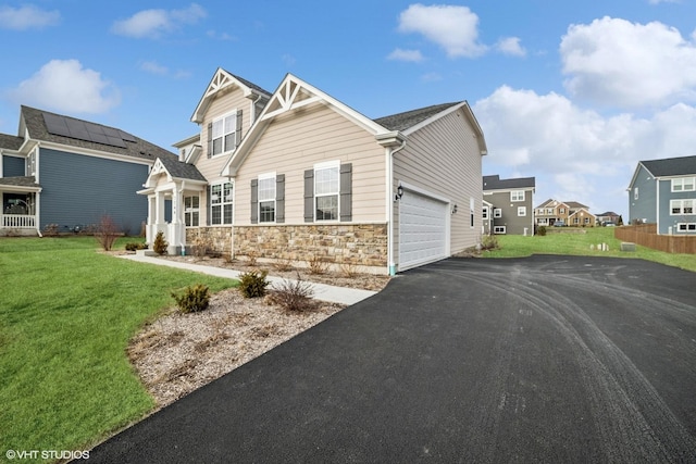 view of front of home with aphalt driveway, a front yard, stone siding, and an attached garage