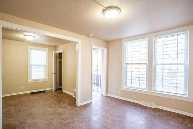 empty room featuring baseboards, visible vents, and a textured ceiling