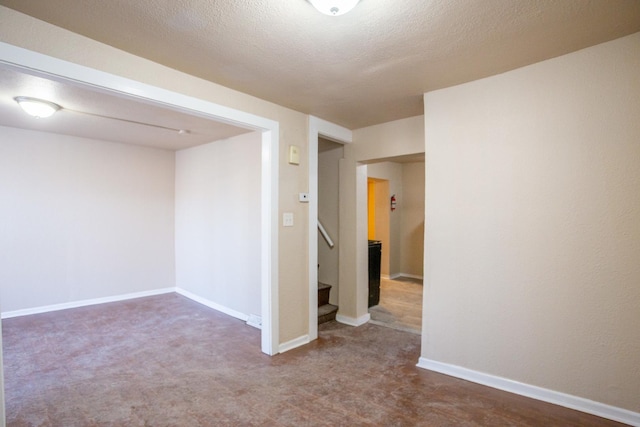 empty room with stairway, baseboards, and a textured ceiling