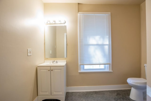 half bath with toilet, baseboards, and vanity