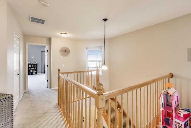 hallway with visible vents, carpet, an upstairs landing, and baseboards