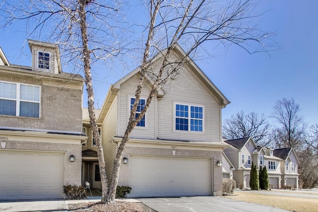 traditional-style home featuring an attached garage, concrete driveway, and brick siding