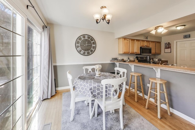 dining area with light wood-style floors, visible vents, baseboards, and an inviting chandelier