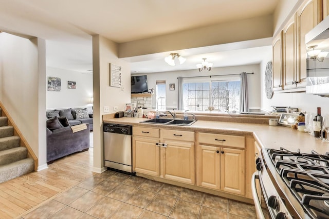 kitchen with light countertops, light brown cabinetry, appliances with stainless steel finishes, open floor plan, and a sink