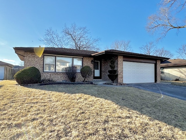 single story home featuring a garage, driveway, brick siding, and a front yard