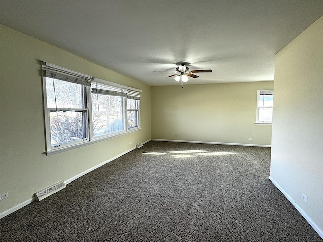 unfurnished room featuring ceiling fan, dark colored carpet, visible vents, and baseboards