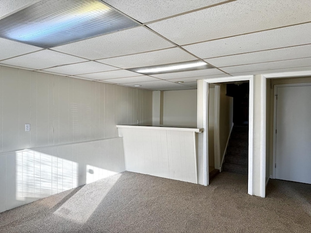 unfurnished room featuring a paneled ceiling, carpet, and stairway