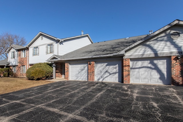 view of front of home featuring a garage, brick siding, a shingled roof, and aphalt driveway