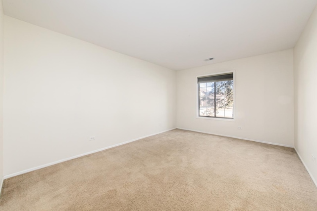 spare room with light carpet, visible vents, and baseboards