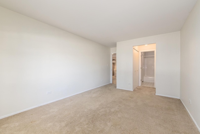 unfurnished bedroom featuring ensuite bath, baseboards, and light colored carpet