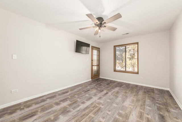 empty room with a ceiling fan, visible vents, baseboards, and wood finished floors