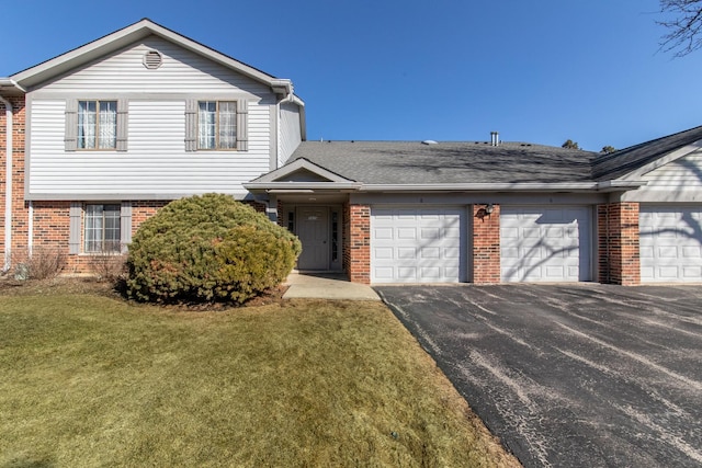 view of front of property with a garage, brick siding, a front lawn, and aphalt driveway