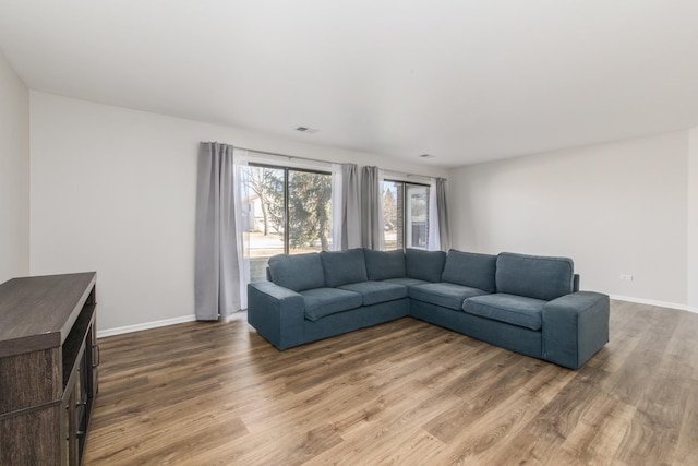 living room featuring wood finished floors, visible vents, and baseboards