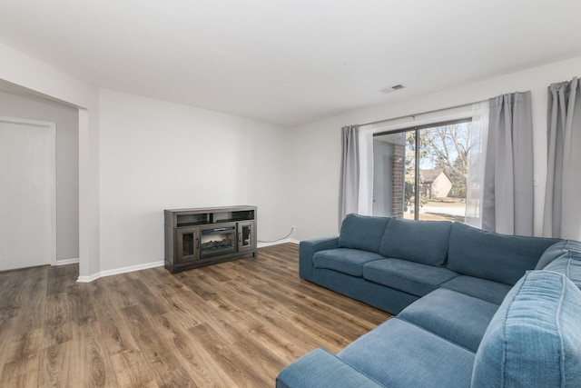 living area featuring baseboards, visible vents, and wood finished floors