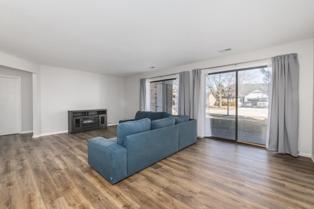 living room with baseboards, visible vents, and wood finished floors