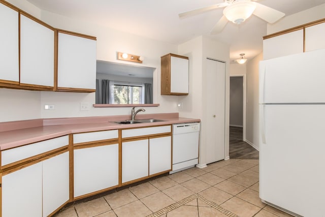 kitchen with white appliances, a sink, and white cabinetry