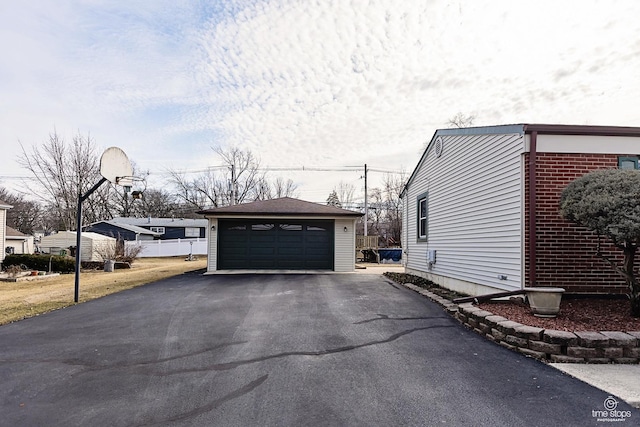 view of property exterior with brick siding, a detached garage, and an outbuilding