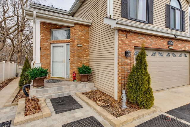 property entrance with an attached garage, fence, and brick siding