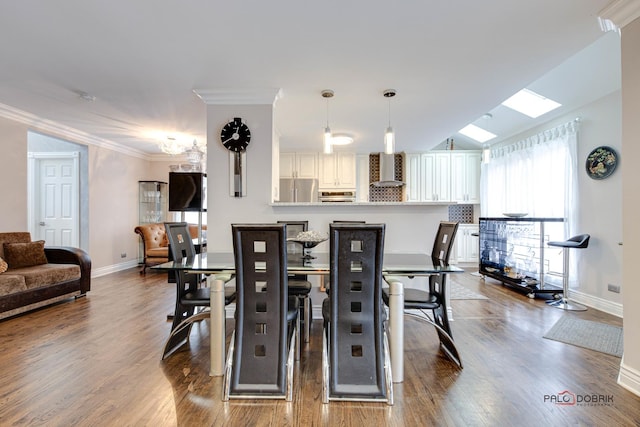 dining room with crown molding, baseboards, and wood finished floors