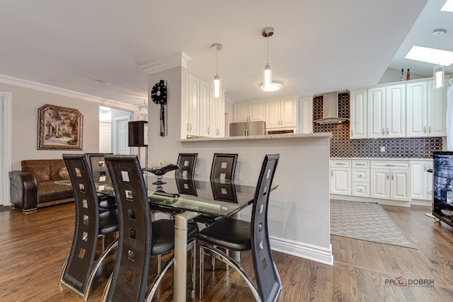 dining space with a skylight, crown molding, and wood finished floors