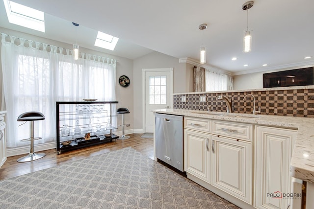 kitchen featuring light wood finished floors, decorative backsplash, a sink, vaulted ceiling with skylight, and dishwasher