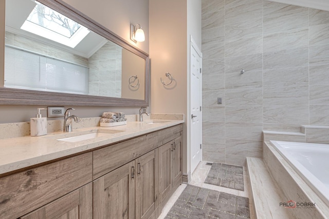 full bathroom featuring double vanity, lofted ceiling with skylight, a relaxing tiled tub, and a sink