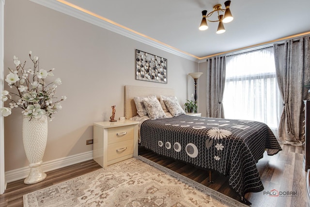 bedroom featuring baseboards, wood finished floors, and crown molding