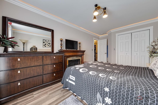 bedroom with a closet, a fireplace, crown molding, and wood finished floors