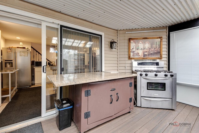 kitchen featuring stainless steel appliances, light stone counters, and light wood finished floors