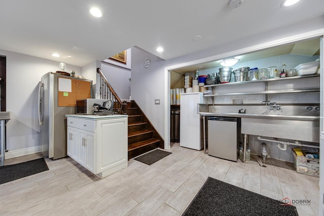 kitchen featuring white microwave, fridge, white cabinetry, and wood tiled floor