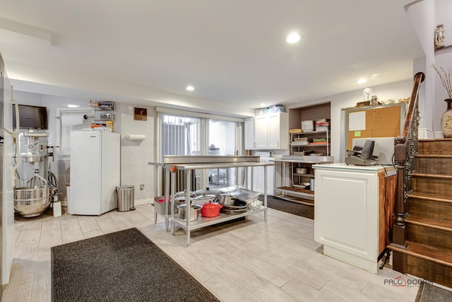 kitchen featuring recessed lighting, wood tiled floor, freestanding refrigerator, and white cabinetry