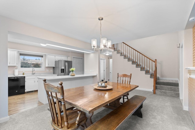 dining room featuring light colored carpet, a notable chandelier, baseboards, and stairs