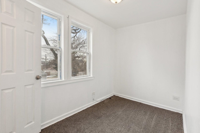 empty room featuring baseboards and dark carpet