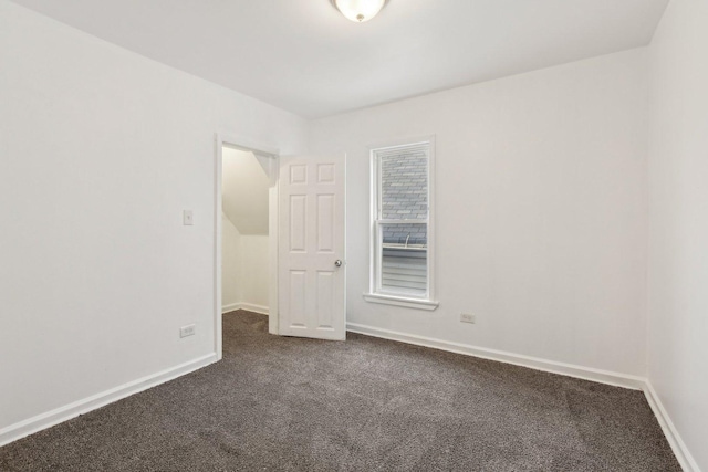 spare room with dark carpet and baseboards