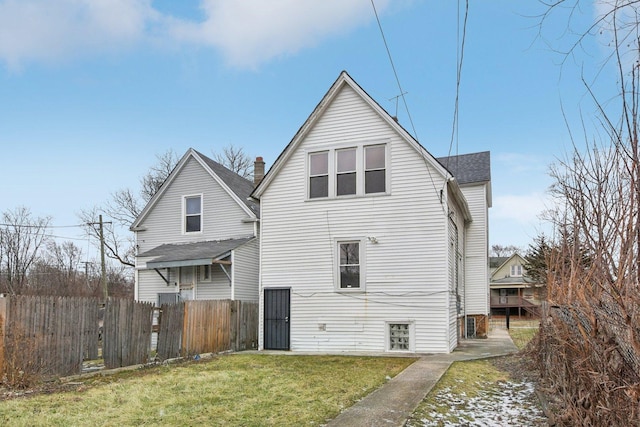 back of property with a lawn and fence