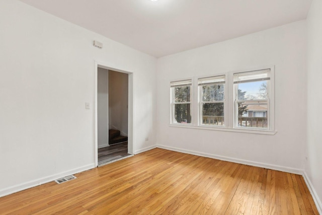 empty room featuring baseboards, visible vents, and light wood-style floors